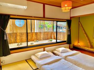 
a hotel room with two beds and a window at Guest House Oumi in Kyoto
