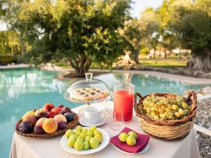 - une table avec des fruits et des jus à côté de la piscine dans l'établissement Trulli Uliveto Acquafonda, à Alberobello