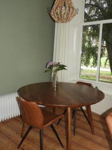una mesa de comedor con sillas y un jarrón con flores en Het Ellerhoes, en Bedum