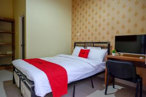 a bedroom with a bed and a desk and a television at RedDoorz @ Jalan Bali Cilacap in Gumilir