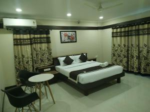 a bedroom with a bed and a table and chairs at Hotel Rose Mansion Manyata Tech Park in Bengaluru +8 photos