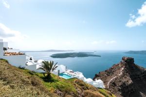 
a large white boat sitting on top of a lush green hillside at Grace Hotel Santorini, Auberge Resorts Collection in Imerovigli
