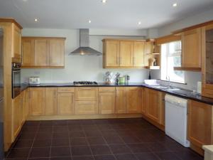 a kitchen with wooden cabinets and black counter tops at Madams Hill House Killarney in Killarney