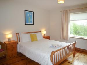 a bedroom with a bed with white sheets and a window at Madams Hill House Killarney in Killarney
