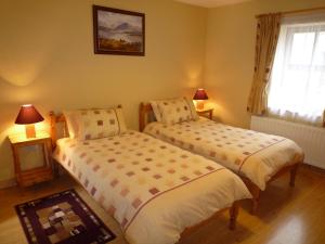 two beds in a room with two lamps and a window at Lakeside Lodge Bantry in Bantry