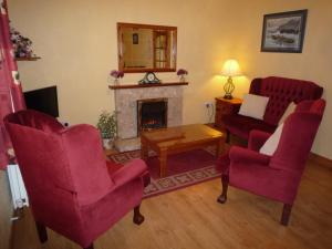 a living room with red chairs and a fireplace at Lakeside Lodge Bantry in Bantry