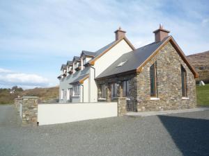 a large stone house with a white wall in front of it at Sea View Holiday Home Sheeps HeadBantry in Bantry