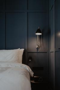 a blue bedroom with a bed and a lamp at The Nox Hotel in Utrecht