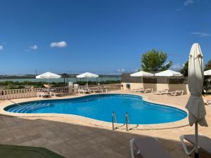 a large swimming pool with chairs and umbrellas at Apartamentos Paya II in Es Pujols