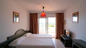 a bedroom with a bed and a large window at Apartamentos Paya II in Es Pujols