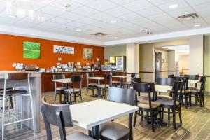 a restaurant with tables and chairs and a bar at Sleep Inn & Suites in Hobbs