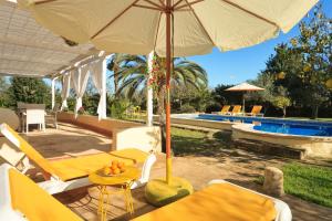 un patio con mesa y sombrilla junto a la piscina en Cana Joana, en Santa Margalida