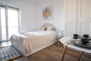 biała sypialnia z łóżkiem i stołem w obiekcie Rossani Suites&Aparts w mieście Bari