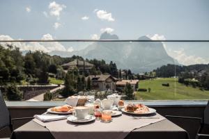 una mesa con platos de comida y vistas a la montaña en Hotel Alpenflora, en Castelrotto