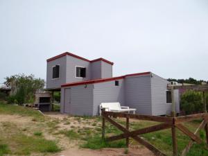 uma pequena casa branca com um banco à frente em AMBRA em Punta Del Diablo