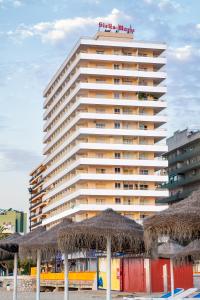 un alto edificio con ombrelloni di paglia sulla spiaggia di Apartamentos Stella Maris - Marcari SL a Fuengirola