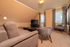 a living room with a couch and a television at Hotel Wasserschlößchen in Naumburg