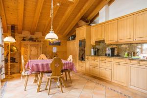 una cocina con armarios de madera, mesa y sillas en Apartment Stotzhalten DG - GRIWA RENT AG, en Grindelwald