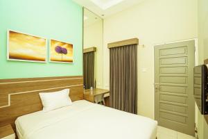 1 dormitorio con 1 cama blanca y TV en Ardhya Guesthouse Syariah by ecommerceloka en Sidoarjo