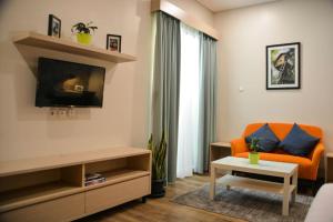 a living room with an orange couch and a tv at Treehouse Suites - Boutique Serviced Apartment in Jakarta