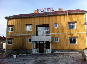 謝萊夫特奧的住宿－Hotell Stensborg，黄色建筑,上面有酒店标志