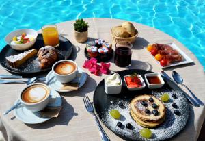 a table with breakfast foods and drinks on a table by a pool at Hotel Costa dei Fiori in Santa Margherita di Pula