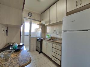 a kitchen with a white refrigerator and a counter top at Apto Guarujá - Asturias in Guarujá