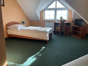 een slaapkamer met een bed, een bureau en een raam bij Hotel Arkadia in Klecza Górna