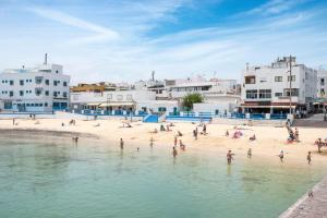 a group of people on a beach near the water at Calas Beach Corralejo in Corralejo