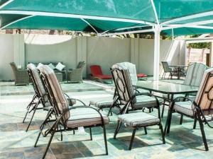 un gruppo di sedie e un tavolo con ombrellone verde di Monacco Guest house a Bronkhorstspruit