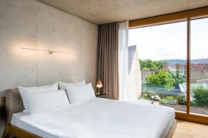 um quarto com uma grande cama branca e uma grande janela em Hotel Krone Design B&B em Weil am Rhein