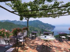 a patio with tables and chairs and a view of the ocean at Hotel Parsifal - Antico Convento del 1288 in Ravello