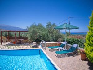 a swimming pool with two chairs and an umbrella at Villa Afrati Sea Views Pool AC in Plaka