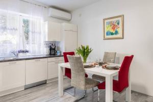 una cucina con tavolo bianco e sedie rosse di Apartman BUKI **** a Spalato (Split)