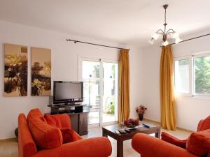 sala de estar con sillas de color naranja y TV de pantalla plana en Villa Eros Spartia Kefalonia en Spartia
