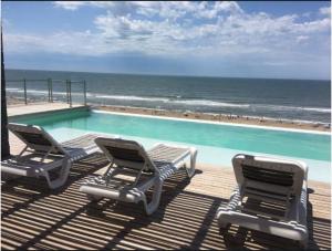 two chairs and a swimming pool next to the ocean at Los Pinos Pinamar in Pinamar