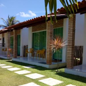 ein Haus mit einer Terrasse und einem Essbereich in der Unterkunft Pousada Villa Minduba in Japaratinga