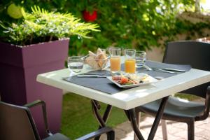 una mesa con un plato de comida y vasos de zumo de naranja en Kyriad Hotel Lyon Givors, en Givors