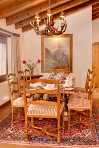 una sala da pranzo con tavolo, sedie e lampadario pendente di Chalet Zen Zermatt, 100m from Ski Lift and Piste a Zermatt