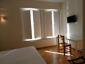 a bedroom with a bed and a desk and a chair at Fado Bed & Breakfast - Santos in Lisbon