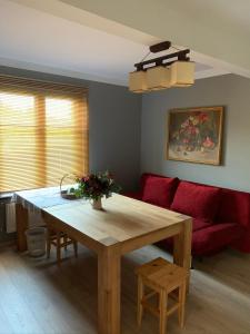 Hostel Kastaņas في Lielvārde: غرفة معيشة مع طاولة خشبية وأريكة حمراء