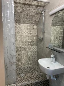 W łazience znajduje się prysznic i biała umywalka. w obiekcie Hostel Kastaņas w mieście Lielvārde