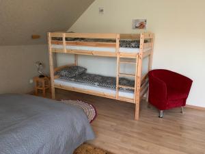 a bedroom with two bunk beds and a red chair at Hostel Kastaņas in Lielvārde