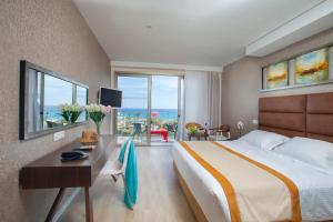 a hotel room with a bed and a desk and windows at Faros Hotel Ayia Napa in Ayia Napa