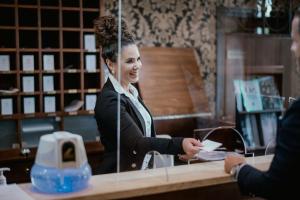 Eine Frau lächelt, wenn sie einem Kunden die Hand schüttelt in der Unterkunft Boutique Hotel Annuska in Balatonfüred