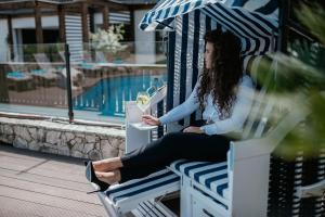 a woman sitting on a bench with an umbrella at Boutique Hotel Annuska in Balatonfüred