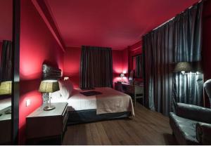 帕拉米夏Theasis Hotel Paramythia的卧室设有红色的墙壁、一张床和一张沙发