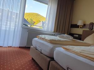 two beds in a hotel room with a large window at Kurparkhotel-Gemünd in Gemünd