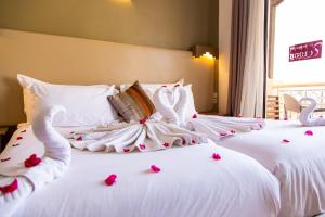 two beds with white sheets and pink rose petals on them at Borjs Hotel Suites & Spa in Agadir