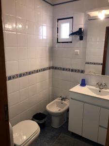 un bagno bianco con un water e un lavandino di Cliff House next to beach a Ericeira Altre 33 foto